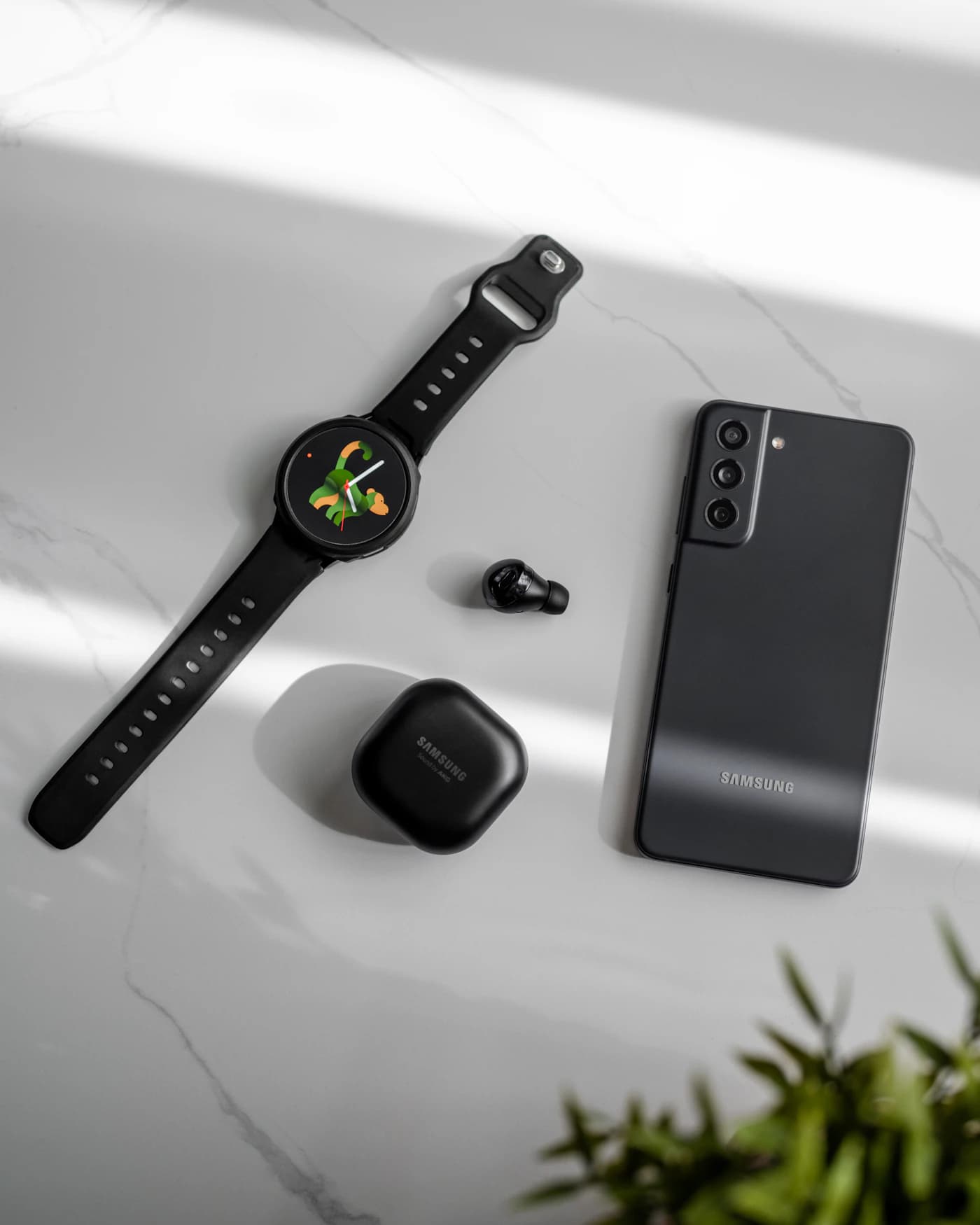 Smartwatch and wireless earbuds on a marble surface